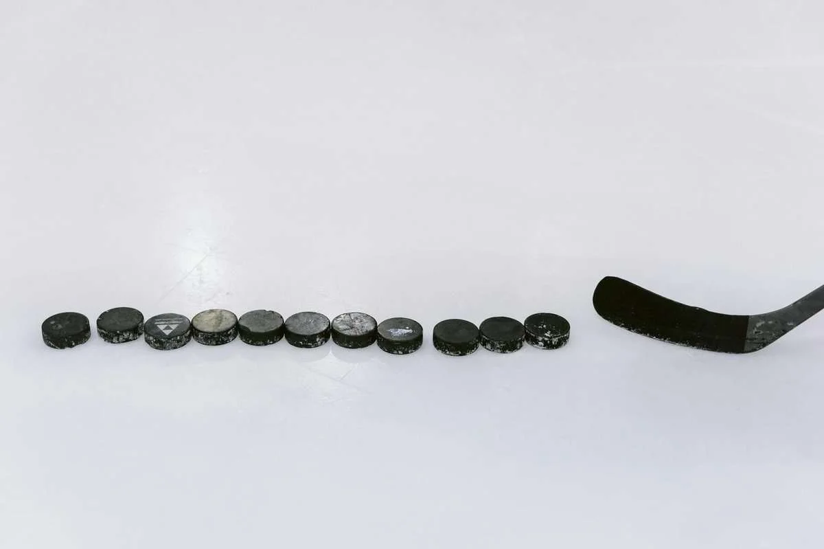 hokej online: A row of hockey pucks and a stick on an ice rink, perfect