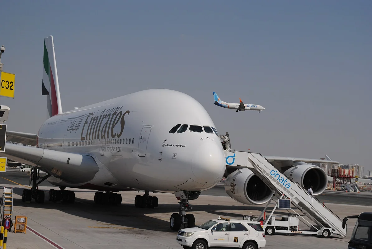 Emirates letadlo na letišti v Dubaji s přistávajícím flydubai letounem