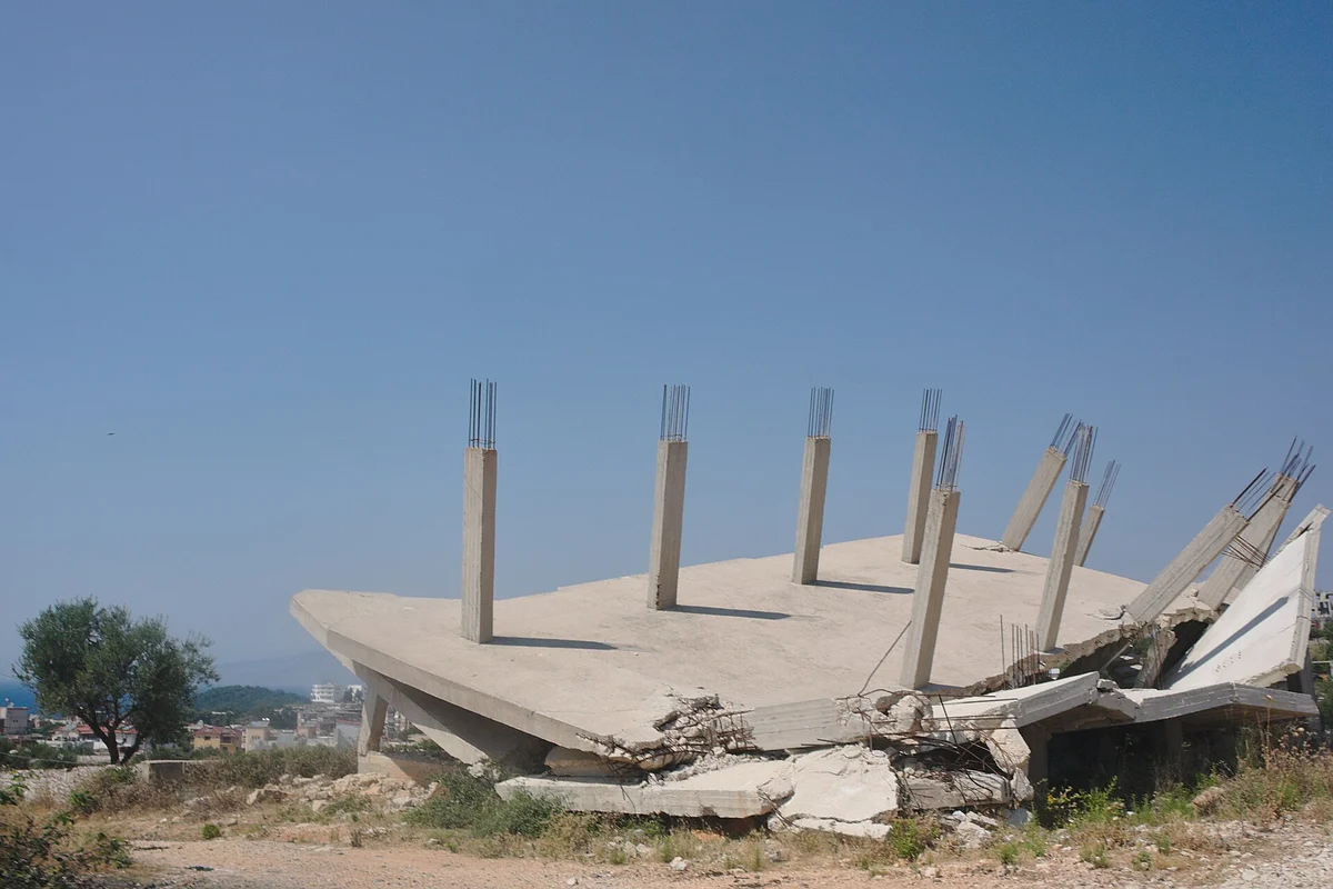 Zbořená černá stavba z betonu s odhalenou armaturou po nařízené demolici
