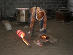 foundry worker pouring molten metal in industrial bronze foundry