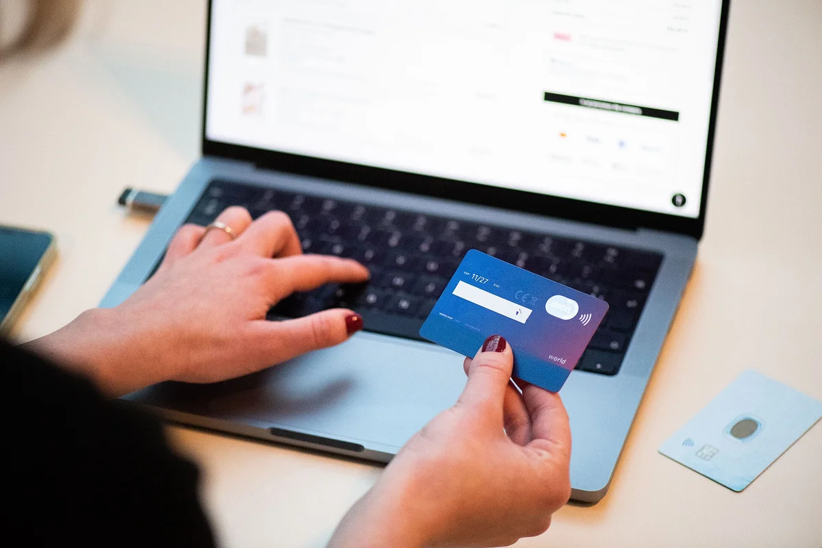 Kobieta sprawdzająca fałszywy sklep internetowy kartą kredytową przy laptopie