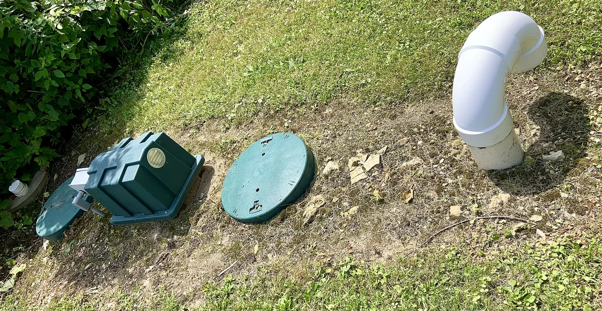 Septička jama u dvorištu: zeleni poklopac revizijskog otvora i odzračna cijev na travnjaku