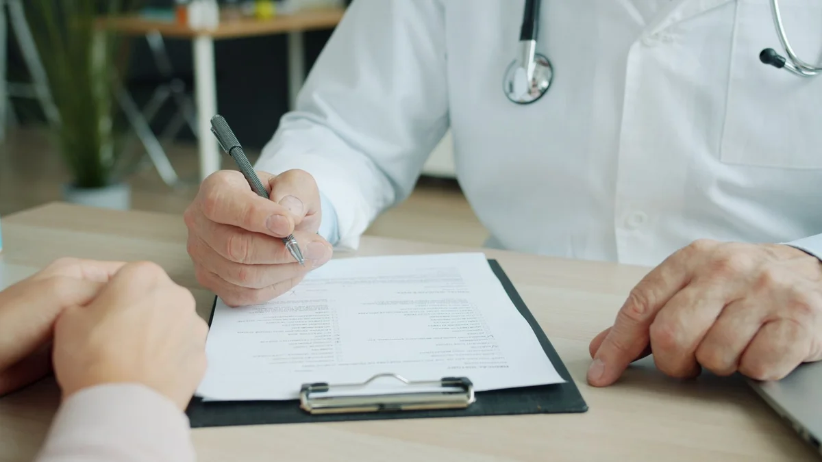 Medic completează documente pentru asigurare de sănătate în cabinet