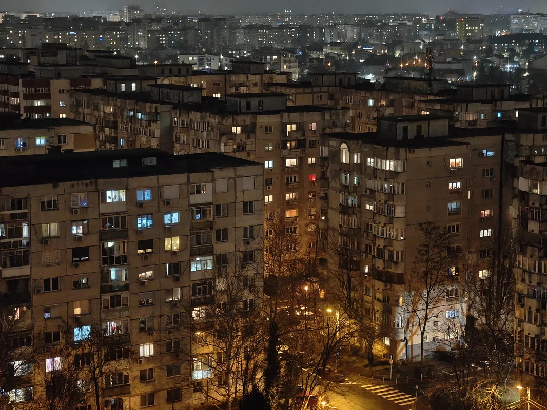 Blocuri de locuințe iluminate noaptea în București, simbol pentru viza de flotant și riscurile proprietarului