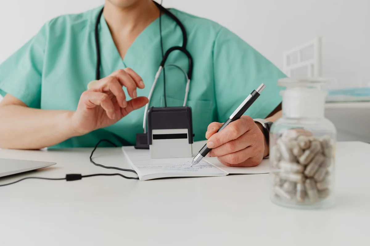 Medic aplică ștampila pe certificat concediu medical la birou