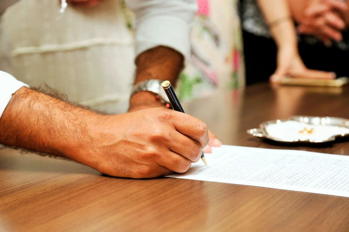 Person signing official document, symbolizing sworn translation certification in Spain
