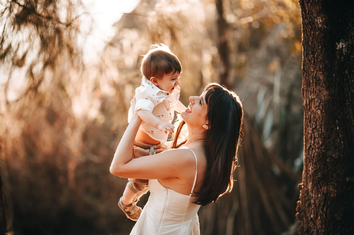 Mother lifting joyful child outdoors, symbolizing Poland's 800+ child benefit