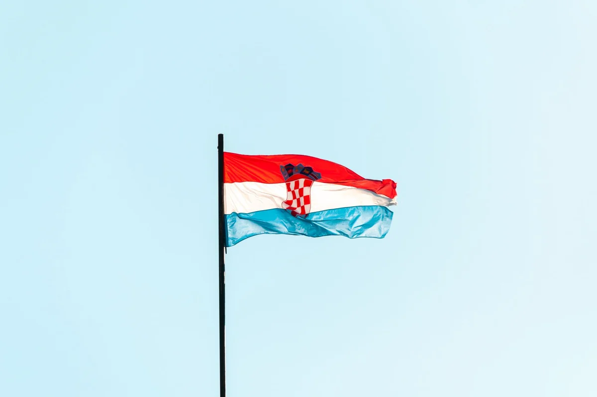 Croatian flag waving on a pole against pale sky, symbolising Croatian citizenship by naturalization